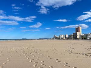 una playa con huellas en la arena y una ciudad en Apartment Gandía Playa 3000, en Gandía