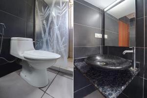 a bathroom with a toilet and a black wall at FabHotel Stayz Inn US Consulate in Chennai