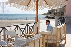 a man sitting at a table under an umbrella on the beach at Portamarina in Vieste