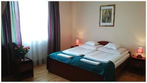 a bed in a bedroom with two lamps and towels at Hotel GoGreen *** in Kraków