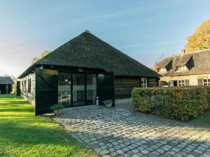 una casa con techo negro y patio en Landgoed Ulvenhart en Gouwelaar