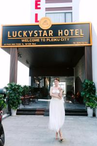 una mujer con un vestido blanco parada frente a un hotel en LuckyStar Hotel en Pleiku