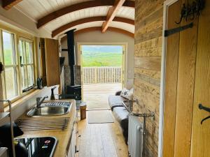 a kitchen with a sink and a couch in a room at Shepherds Hut at Maes Uldale in Uldale