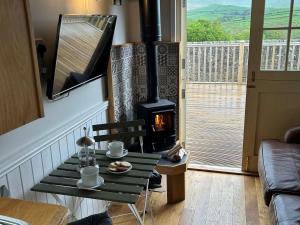 a fireplace in a living room with a table and a stove at Shepherds Hut at Maes Uldale in Uldale