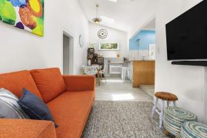 salon z pomarańczową kanapą i kuchnią w obiekcie Peaceful & private city cottage with carparks w mieście Wellington