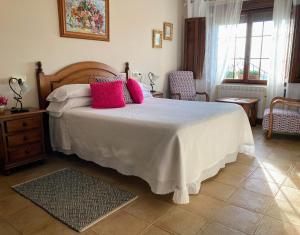 a bedroom with a large bed with pink pillows at Posada Las Torres in Yuso