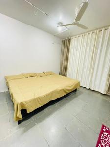 1 dormitorio con 1 cama con manta amarilla en Tuljai Homestay, en Tuljapur