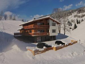 twee auto's geparkeerd in de sneeuw voor een huis bij Modern chalet with sauna near ski area in Saalbach Hinterglemm Salzburgerland in Saalbach Hinterglemm