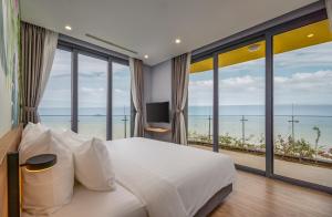 a bedroom with a large white bed and large windows at Flamingo Ibiza Hải Tiến in Nam Khê