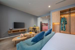 a living room with a blue couch and a tv at Flamingo Ibiza Hải Tiến in Nam Khê