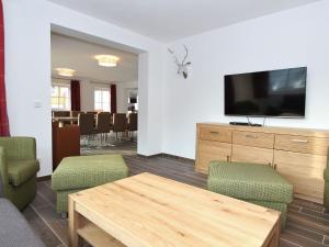ein Wohnzimmer mit einem TV, einem Tisch und Stühlen in der Unterkunft Modern chalet with sauna near ski area in Saalbach Hinterglemm Salzburgerland in Saalbach-Hinterglemm