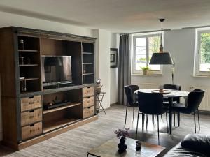 a living room with a table and a large entertainment center at Apartmenthaus Villa Lindenbühl in Mühlhausen