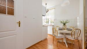 uma cozinha branca com mesa e cadeiras em Flatbook - In the Heart of Old Town Apartments Mariacka em Gdansk