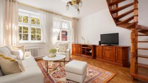 uma sala de estar com um sofá branco e uma televisão em Flatbook - In the Heart of Old Town Apartments Mariacka em Gdansk
