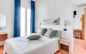Hotel Delfino في ميلانو ماريتيما: غرفة نوم بسرير أبيض مع ستائر زرقاء