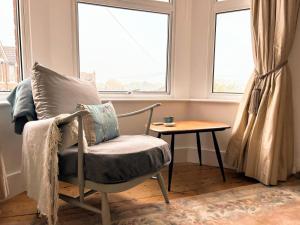 Large Sunny King-Size En-Suite في هاستينغز: غرفة بها كرسي وطاولة ونوافذ