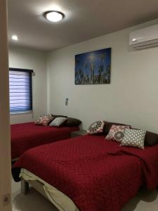 a bedroom with two beds and a painting on the wall at Playa Sur departamento centrico y turistico in Mazatlán