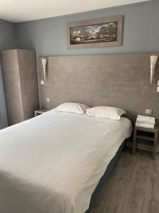 una camera da letto con un grande letto bianco con due cuscini di Hôtel Le Home Saint Louis a Versailles
