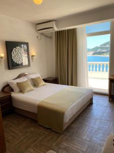 a bedroom with a large bed with a large window at Hotel Kuč in Budva