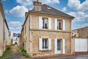 une vieille maison en briques avec volets blancs dans une rue dans l'établissement La Maison du Pêcheur - A 250 m de la plage, à Saint-Aubin-sur-Mer