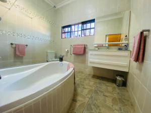 baño blanco con bañera y ventana en Rondeletia Cottage Guesthouse - premium self catering, en Gillitts