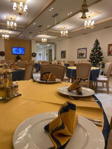 a dining room with a christmas tree and tables and chairs at Grand White City Hotel in Berat