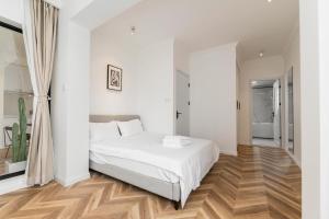 a white bedroom with a white bed and wooden floors at Shanghai Hills&Serendipity Coloured Glaze Family Homestay with 2 Bedrooms Near Line1&2 People Square in Shanghai