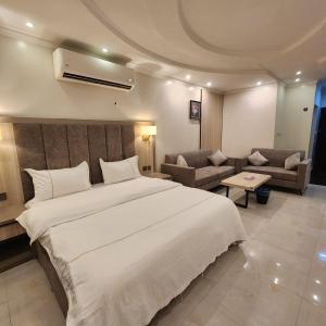 um quarto com uma grande cama branca e um sofá em Blend Hotel em Dammam