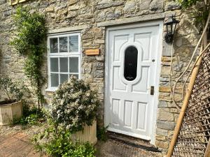 - une porte blanche sur une maison en pierre avec une fenêtre dans l'établissement Farthings Country House Hotel & Restaurant Tunton, à Taunton