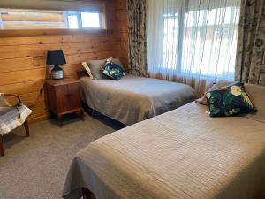 基督城的住宿－The Log Cottage，一间卧室配有两张床和一张带台灯的桌子