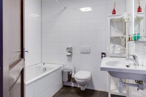 a white bathroom with a toilet and a sink at Hotel Royal Bridges in Delft
