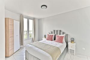 ein weißes Schlafzimmer mit einem großen Bett mit rosa Kissen in der Unterkunft Magnifique 2 pieces aux portes de Paris in Gagny
