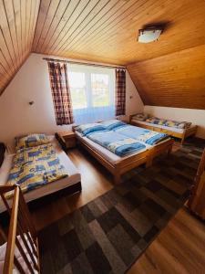 two beds in a room with a wooden ceiling at Chata u pltníka Paľka in Podbiel