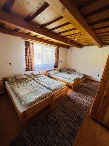 three beds in a room with a window at Chata u pltníka Paľka in Podbiel