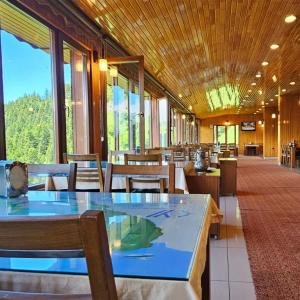 a dining room with tables and chairs and windows at Lahza Hills Resort in Çaykara