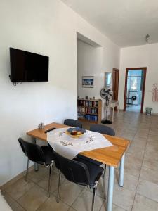 a dining room table with chairs and a television on a wall at Eleni's Apartments in Agios Nikolaos