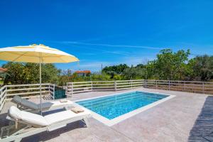a pool with an umbrella and a chair at Villa Sea Stone by Villa Plus in Makris Gialos