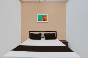 メーラトにあるOYO Hotel Maharaja Palaceのベッドルーム(白いベッド、黒い枕付)