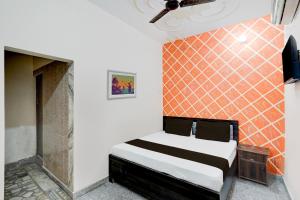 メーラトにあるOYO Hotel Maharaja Palaceのベッドルーム1室(オレンジ色のタイル張りの壁のベッド1台付)