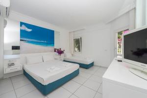 a white room with two beds and a flat screen tv at Bendis Beach Hotel in Akyarlar