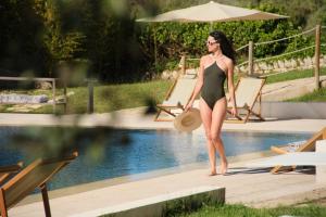 a woman in a bikini standing next to a swimming pool at Es Figueral Nou Hotel Rural & Spa - Adults Only - Over 12 in Montuiri