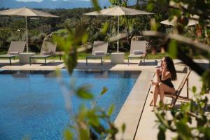una donna seduta su una sedia accanto alla piscina di Es Figueral Nou Hotel Rural & Spa - Adults Only - Over 12 a Montuiri