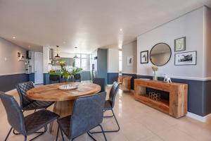 una sala da pranzo con tavolo, sedie e uno specchio di Stylishly Decorated Beachfront apartment w Inverter, 202 Eden a Bloubergstrand