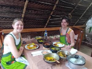 Due donne sedute a un tavolo con cibo di Yaluwa Tourist Rest & cooking class a Anuradhapura