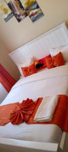 una cama con sábanas blancas y almohadas rojas en Cozy accommodations, en Naivasha