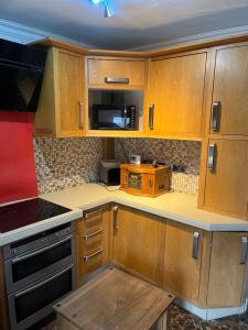 a kitchen with wooden cabinets and a microwave at AICHELON Lodge in Wakefield