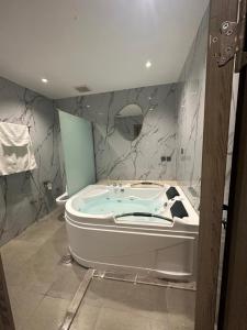 y baño con bañera y paredes de mármol. en SUN SET HOTEL فندق سن ست, en Najrán