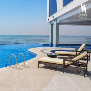 uma piscina com duas espreguiçadeiras e um edifício em Hidd heights bahrain em Ḩālat an Na‘īm
