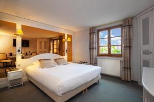 Un dormitorio con una gran cama blanca y una ventana en Hôtel Restaurant Relais De La Poste - Strasbourg Nord, en La Wantzenau