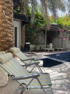 two lounge chairs sitting next to a swimming pool at شاليه كيو آر in Banī Ma‘n